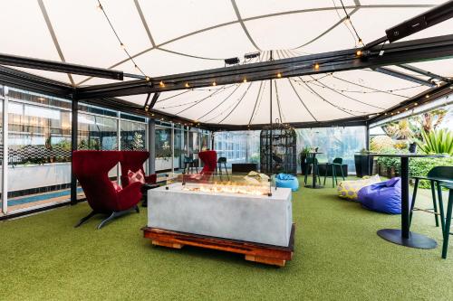 une tente avec des chaises, une table et un parasol dans l'établissement Naumi Hotel Auckland Airport, à Auckland