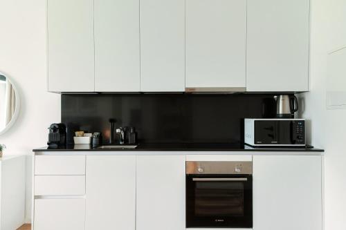 a kitchen with white cabinets and a microwave at Residenza Ticino by Quokka 360 - Modern Oasis near Bellinzona in Bellinzona