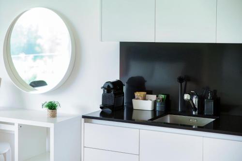a white kitchen with a sink and a mirror at Residenza Ticino by Quokka 360 - Modern Oasis near Bellinzona in Bellinzona