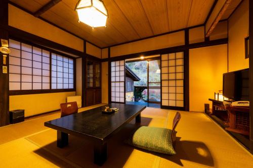 a living room with a table and chairs and windows at Hozantei in Minamioguni