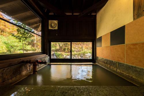 an empty room with a pool of water and windows at Hozantei in Minamioguni