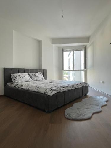 a large bed in a white room with a large window at Skyline Apartment in Pristina