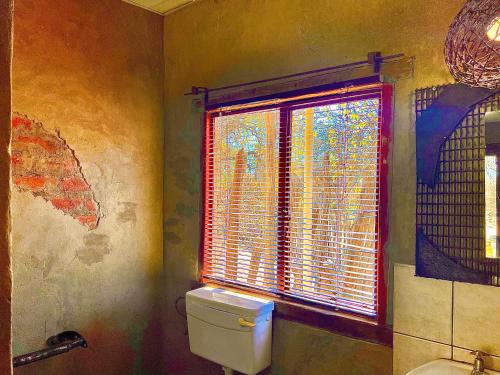 a bathroom with a white toilet and a window at Roy's Rest Camp in Groutfontein