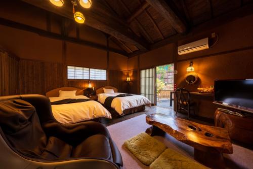 a bedroom with two beds and a tv and a couch at Hozantei in Minamioguni