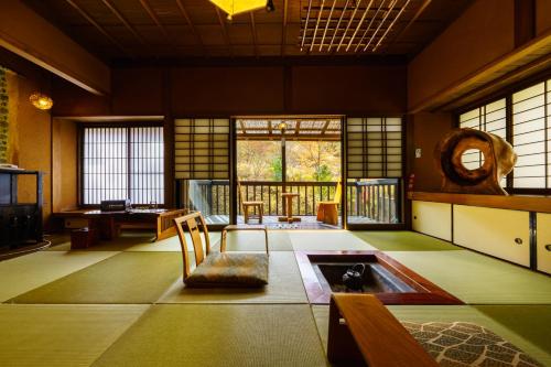 a living room with a table and a chair in a room at Hozantei in Minamioguni