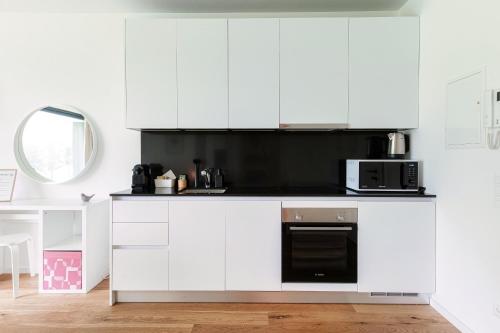 a kitchen with white cabinets and a black microwave at Residenza Ticino by Quokka 360 - Modern Oasis near Bellinzona in Bellinzona