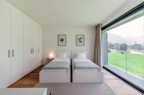 two beds in a room with a large window at Residenza Ticino by Quokka 360 - Modern Oasis near Bellinzona in Bellinzona