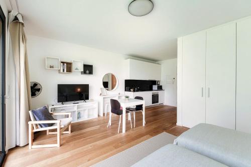 a white living room with a table and a tv at Residenza Ticino by Quokka 360 - Modern Oasis near Bellinzona in Bellinzona