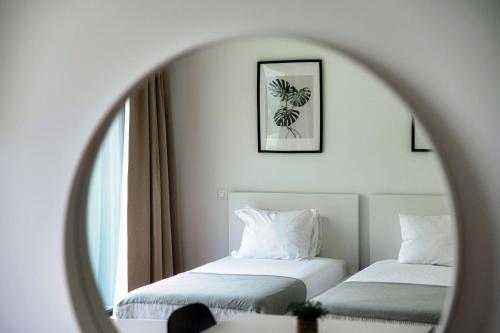 a mirror reflecting two beds in a hotel room at Residenza Ticino by Quokka 360 - Modern Oasis near Bellinzona in Bellinzona