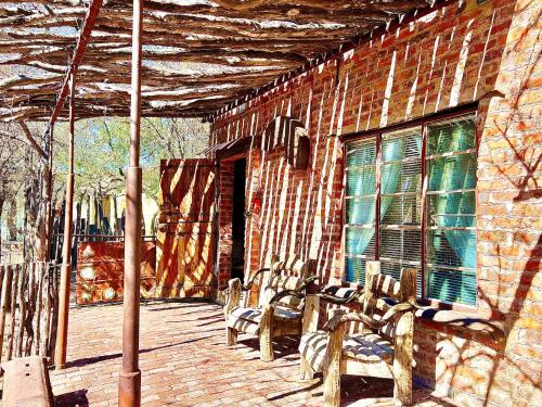 a group of benches sitting on a porch of a brick building at Roy's Rest Camp in Groutfontein