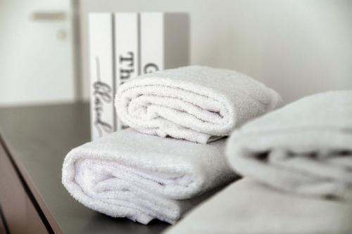 a stack of towels sitting on a counter in a bathroom at Residenza Ticino by Quokka 360 - Modern Oasis near Bellinzona in Bellinzona