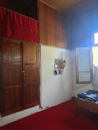 a room with two wooden doors and a red curtain at Homestay Pisang in Bukittinggi