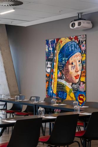 a large painting on the wall in a room with tables at Radisson RED Hotel V&A Waterfront Cape Town in Cape Town