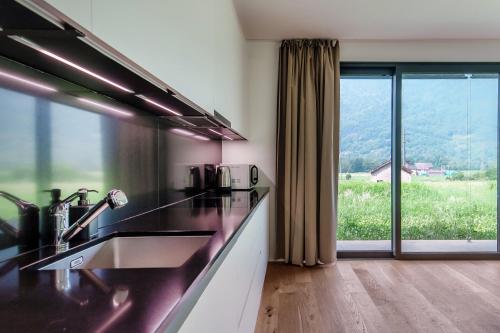 a kitchen with a sink and a large window at Residenza Ticino by Quokka 360 - Modern Oasis near Bellinzona in Bellinzona