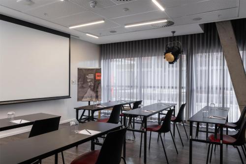 a conference room with tables and chairs and a screen at Radisson RED Hotel V&A Waterfront Cape Town in Cape Town