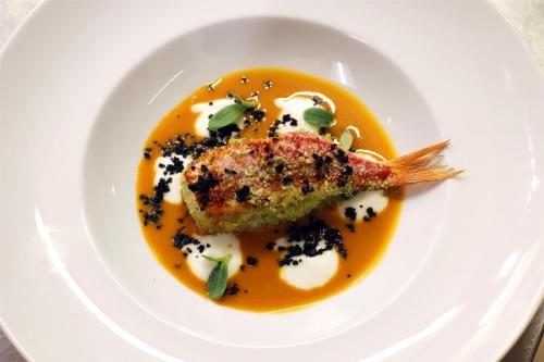 a white plate with a piece of fish in a yellow sauce at Radisson Blu GHR Rome in Rome