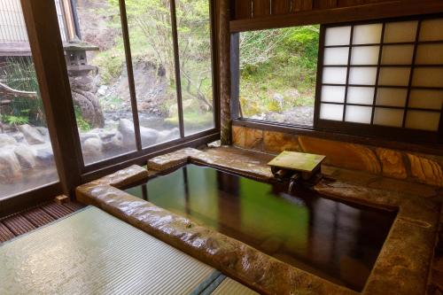 a bath tub in a room with windows at Hozantei in Minamioguni