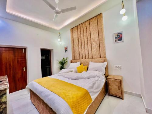 a bedroom with a large bed with a yellow blanket at Dyson Ville in Dehradun