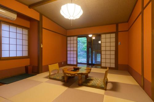 a room with orange walls and a table and chairs at Hozantei in Minamioguni