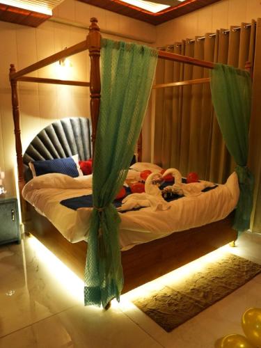 a bedroom with a canopy bed with green curtains at Dyson Ville in Dehradun