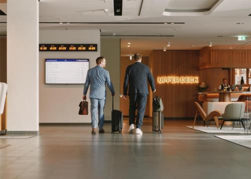 two men walking through an airport with their luggage at Lufthansa Seeheim - More than a Conference Hotel in Seeheim-Jugenheim