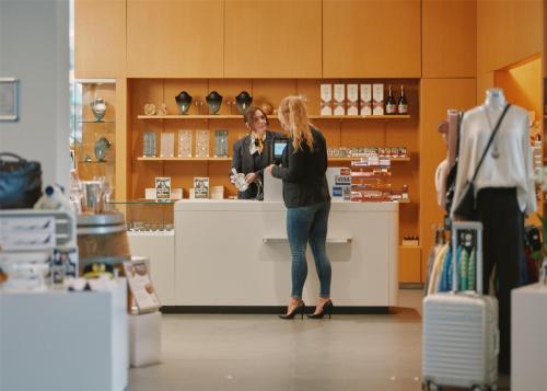 a woman standing at a counter in a store at Lufthansa Seeheim - More than a Conference Hotel in Seeheim-Jugenheim