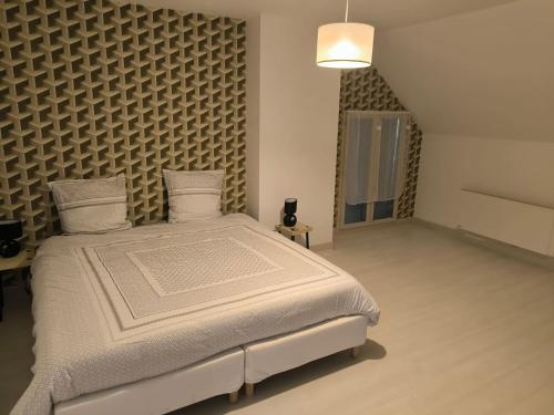 a bedroom with a large bed and a wall at La Maison bleue Paissy in Paissy