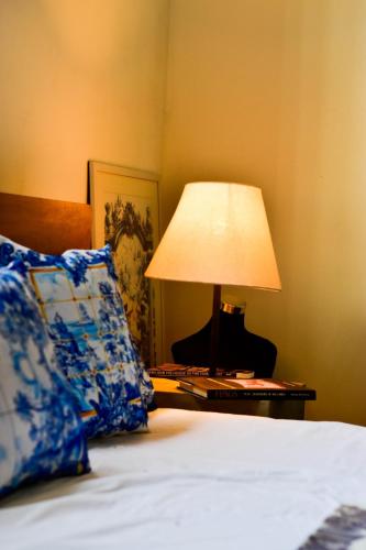 a bed with a lamp on a table next to it at ArtNEST Gallery Stay , Pedlars St , Galle Fort in Galle
