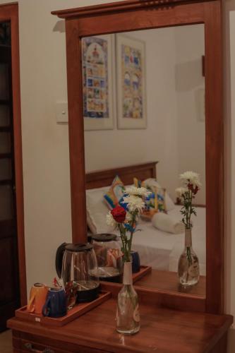 a bedroom with a mirror and two vases with flowers on a table at ArtNEST Gallery Stay , Pedlars St , Galle Fort in Galle