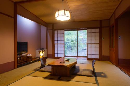a room with a table and chairs and a window at Hozantei in Minamioguni