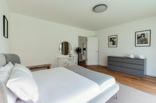 a white bedroom with a bed and a mirror at Residenza Ticino by Quokka 360 - Modern Oasis near Bellinzona in Bellinzona