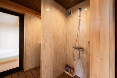 a bathroom with a shower in a wooden wall at AtamiOnsen Nagahamaen in Atami