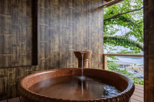a bath tub in a room with a window at AtamiOnsen Nagahamaen in Atami