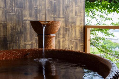 a water fountain in front of a wooden fence at AtamiOnsen Nagahamaen in Atami