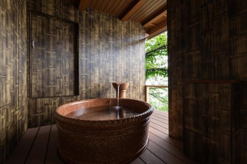 a bath tub in a room with a window at AtamiOnsen Nagahamaen in Atami