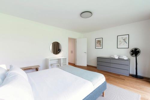 a white bedroom with a bed and a desk at Residenza Ticino by Quokka 360 - Modern Oasis near Bellinzona in Bellinzona