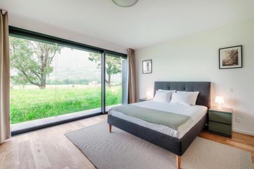 a bedroom with a bed and a large window at Residenza Ticino by Quokka 360 - Modern Oasis near Bellinzona in Bellinzona