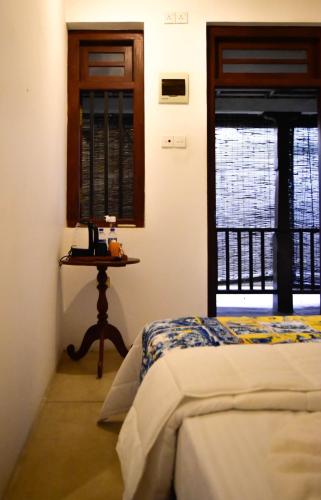 a bedroom with a bed and a table with a window at ArtNEST Gallery Stay , Pedlars St , Galle Fort in Galle