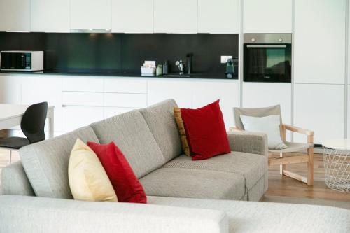 a living room with a gray couch with red and yellow pillows at Residenza Ticino by Quokka 360 - Modern Oasis near Bellinzona in Bellinzona