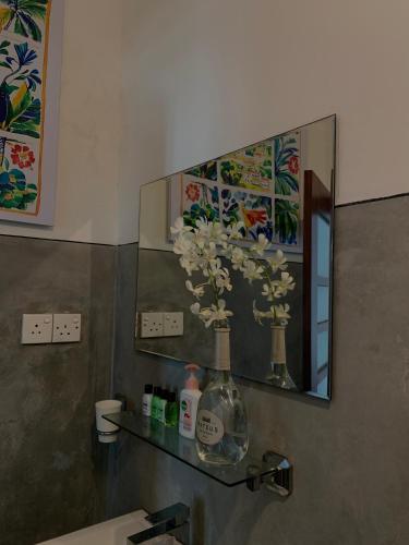a bathroom sink with a mirror and a vase with flowers at ArtNEST Gallery Stay , Pedlars St , Galle Fort in Galle