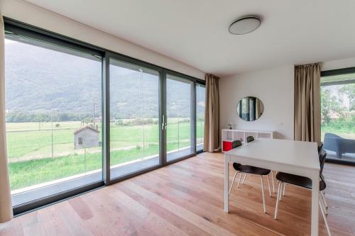 a room with a table and chairs and large windows at Residenza Ticino by Quokka 360 - Modern Oasis near Bellinzona in Bellinzona