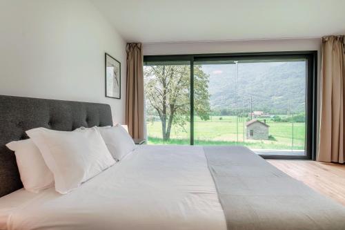 a bedroom with a large bed with a large window at Residenza Ticino by Quokka 360 - Modern Oasis near Bellinzona in Bellinzona
