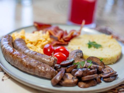a plate of breakfast food with sausage tomatoes and eggs at Somerset Nest Lodge in Somerset West