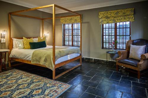 a bedroom with a canopy bed and a chair at Boord Guest House in Stellenbosch