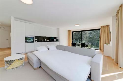a white living room with a couch and a large window at Residenza Ticino by Quokka 360 - Modern Oasis near Bellinzona in Bellinzona