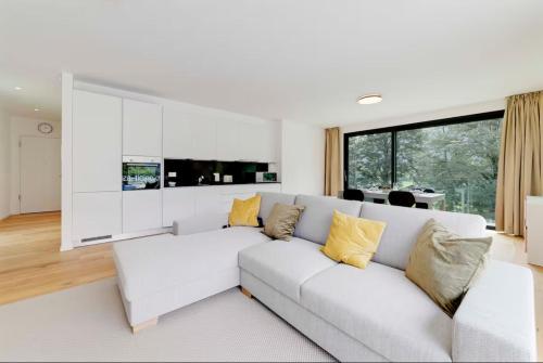 a white living room with a white couch and yellow pillows at Residenza Ticino by Quokka 360 - Modern Oasis near Bellinzona in Bellinzona