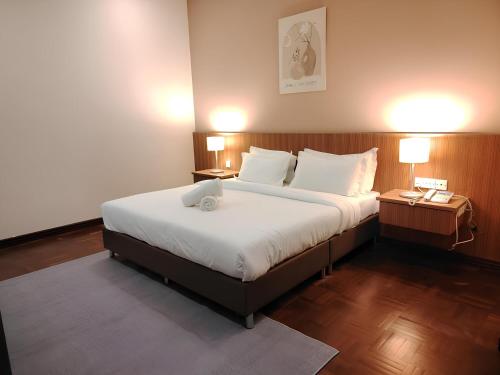 a bedroom with a large bed with two tables and two lamps at Natol Homestay - Sydney Batu Kawa MJC New Townships in Kampong Sandong