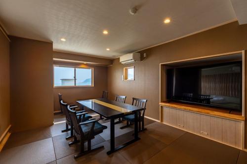 a dining room with a table and a flat screen tv at AtamiOnsen Nagahamaen in Atami