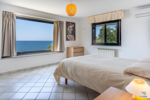 a bedroom with a bed and a view of the ocean at Vero Sicily - Villa Acqua Chiara in Bagheria