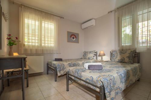 a bedroom with two beds and a desk and windows at My Sunflower in Nea Fokea
